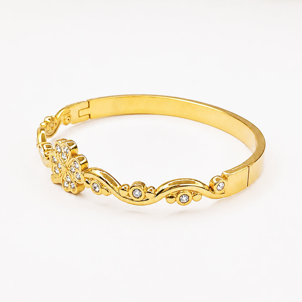 Elegant gold bangle bracelet with a diamond-studded flower and scroll design