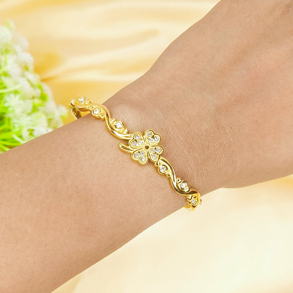 Elegant gold clover-shaped bracelet with sparkling crystals on a person's wrist