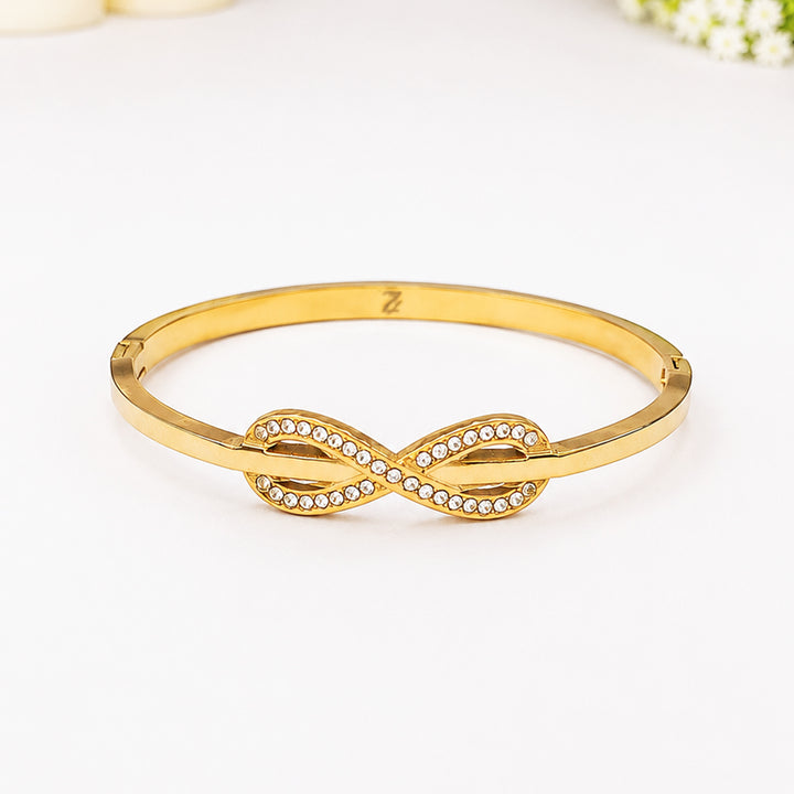 Gold-plated bangle bracelet with a sparkling crystal-encrusted infinity symbol centerpiece