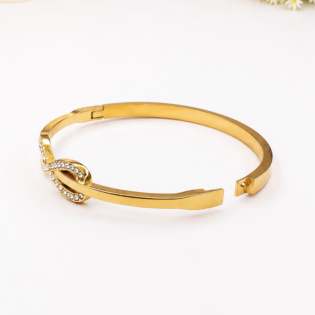 Gold-plated open cuff bracelet with a sparkling rhinestone infinity knot detail