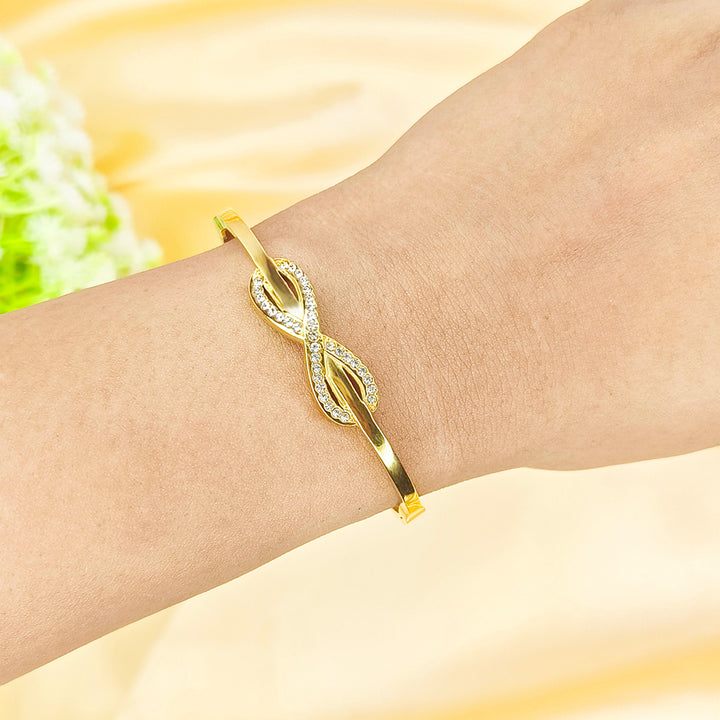Gold-plated infinity symbol bracelet with sparkling crystals on a woman's wrist