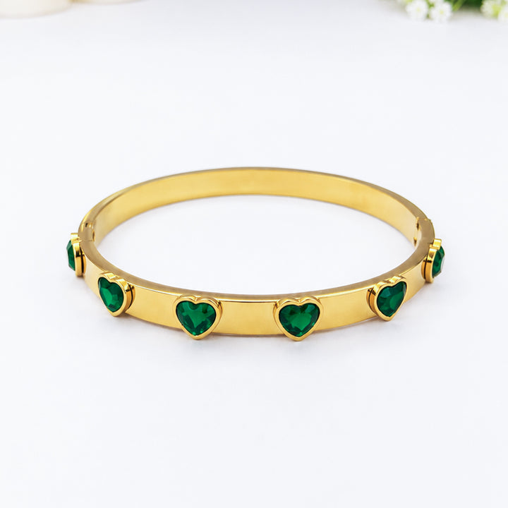 Gold-plated bangle bracelet with inlaid green heart-shaped crystals