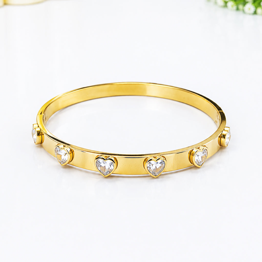 Gold-plated bangle bracelet featuring heart-shaped cubic zirconia crystals