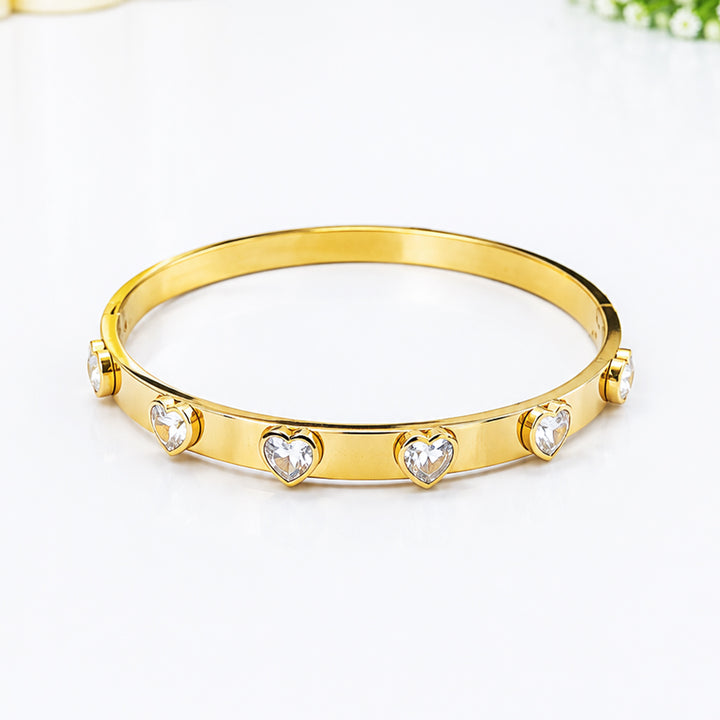 Gold-plated bangle bracelet featuring heart-shaped cubic zirconia crystals