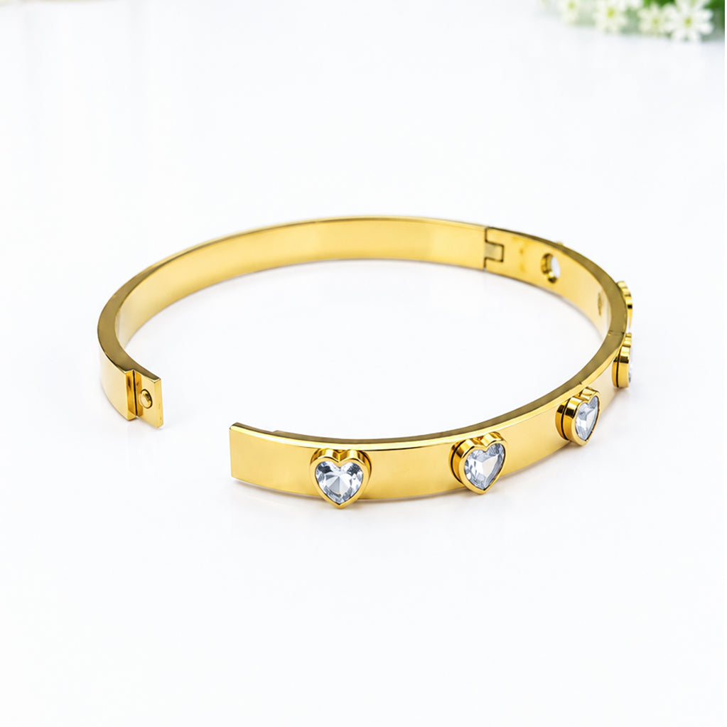 Gold-plated bangle bracelet featuring heart-shaped crystal accents