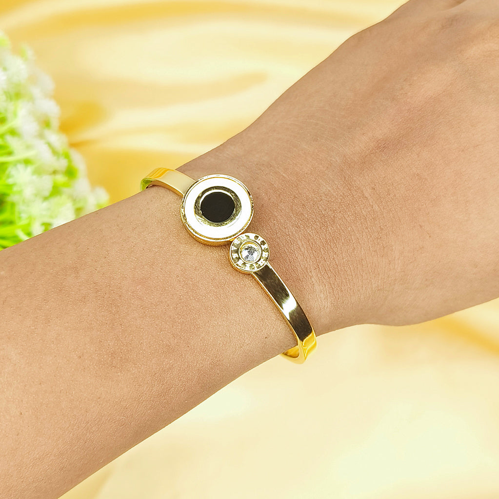 Close-up of a gold-plated bangle with a black center stone and small crystals on a wrist