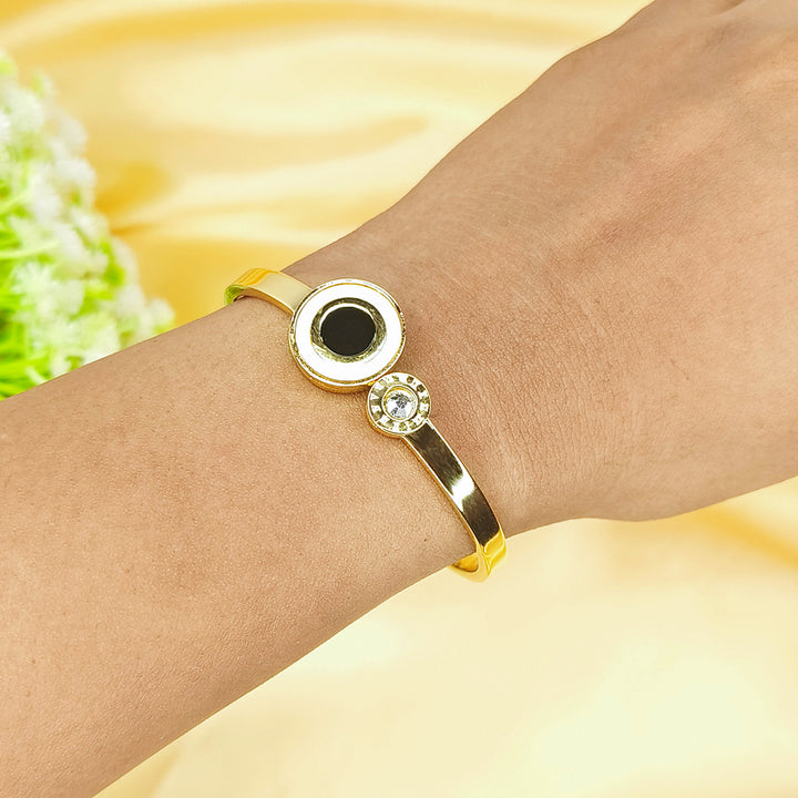 Close-up of a gold-plated bangle with a black center stone and small crystals on a wrist