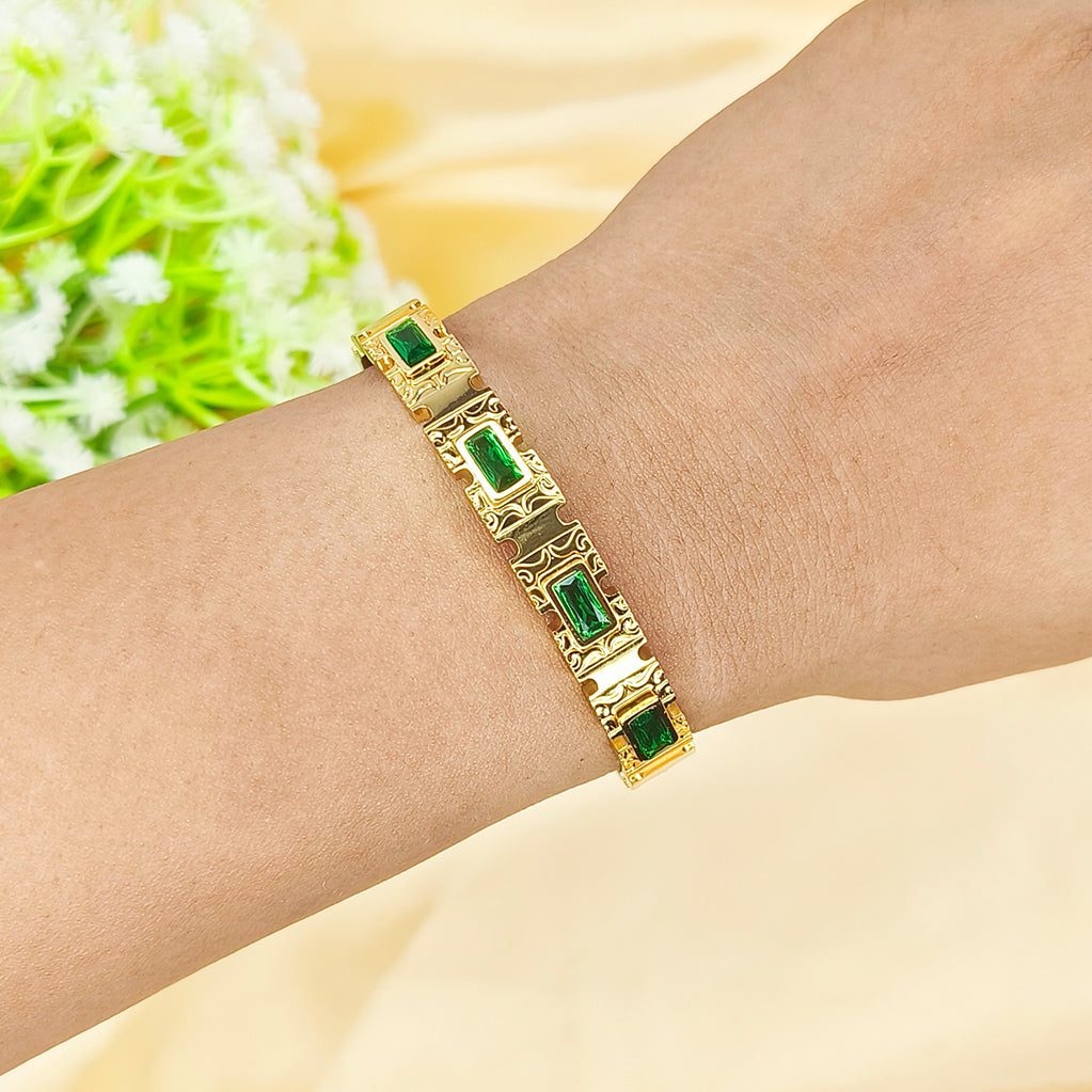 Gold bracelet with rectangular green emerald gemstones on a person's wrist