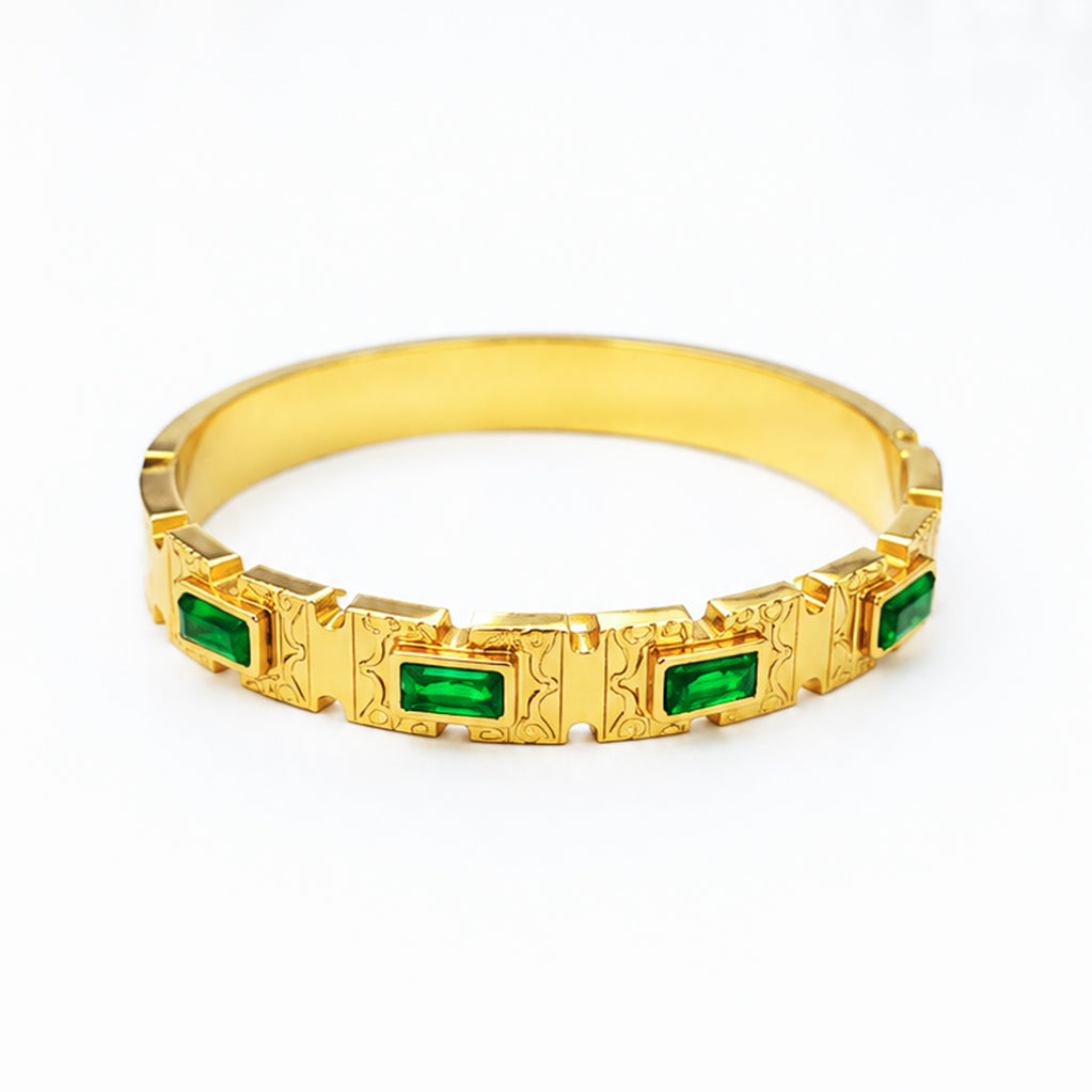 Gold bangle bracelet featuring rectangular emerald green gemstones