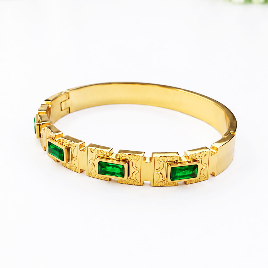 Gold bangle bracelet with rectangular emerald green gemstones