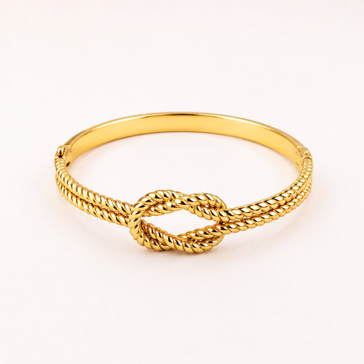 Gold-toned rope knot bangle bracelet on a white background
