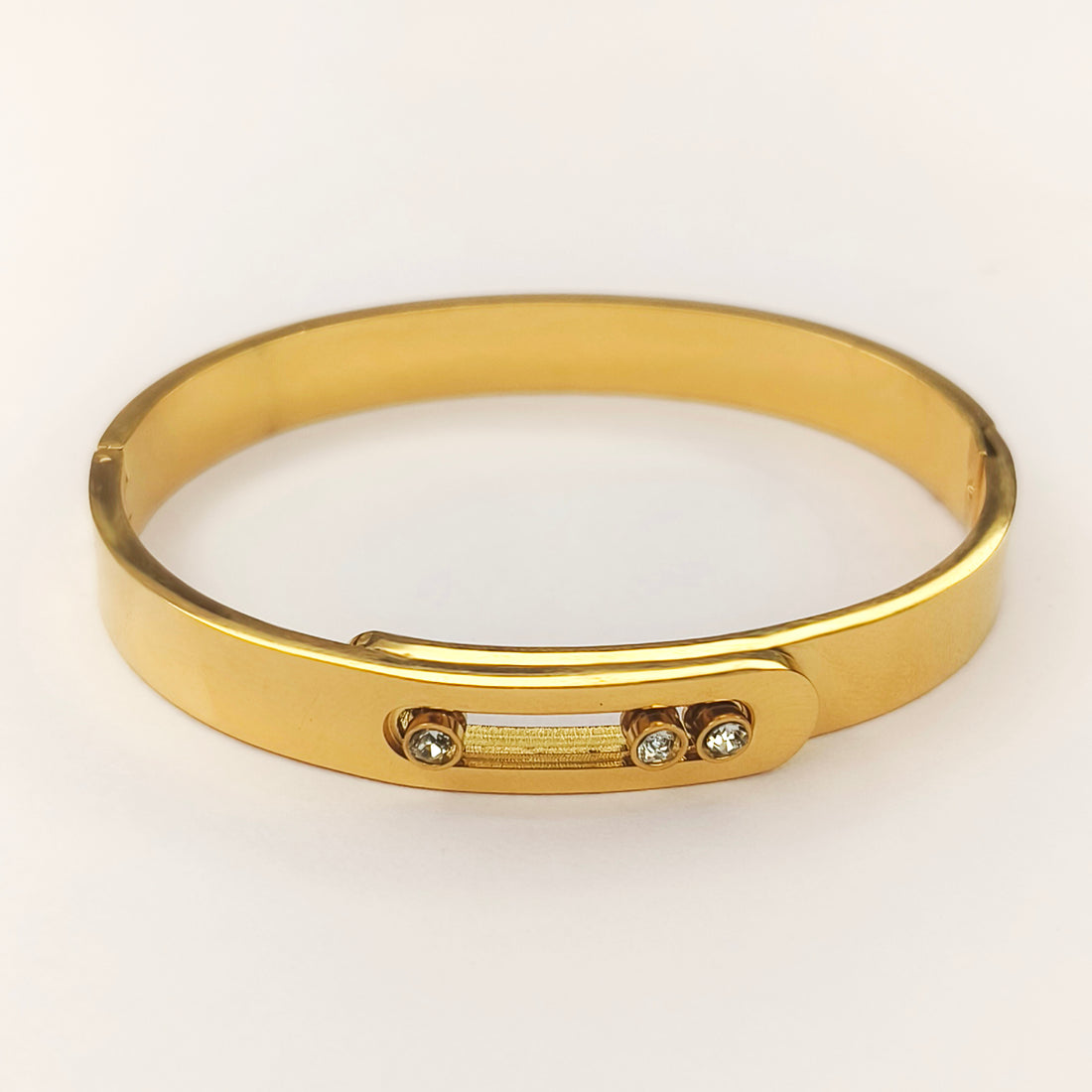 Elegant gold bangle bracelet with small inlaid sparkling stones on a white background