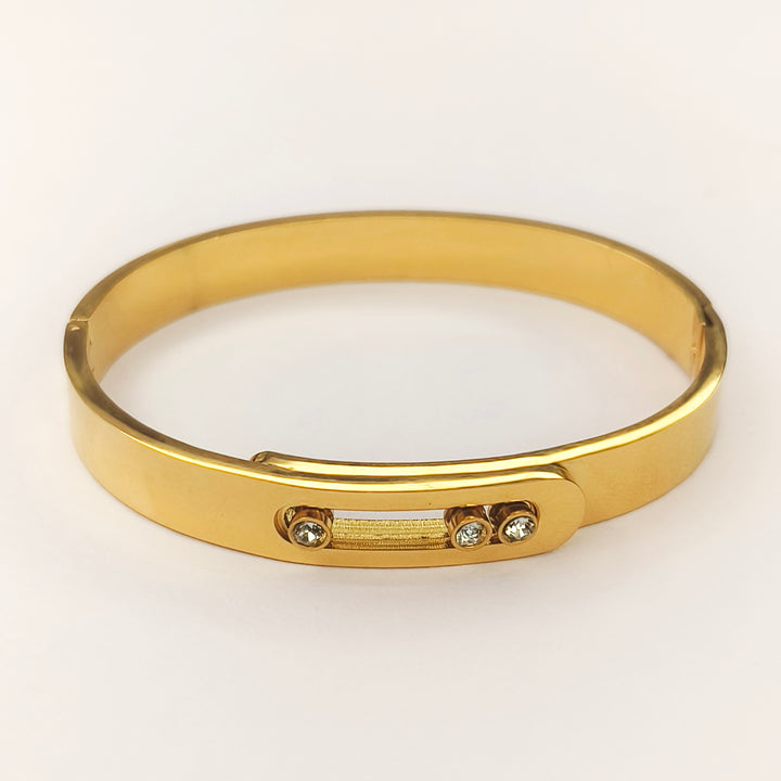 Elegant gold bangle bracelet with small inlaid sparkling stones on a white background