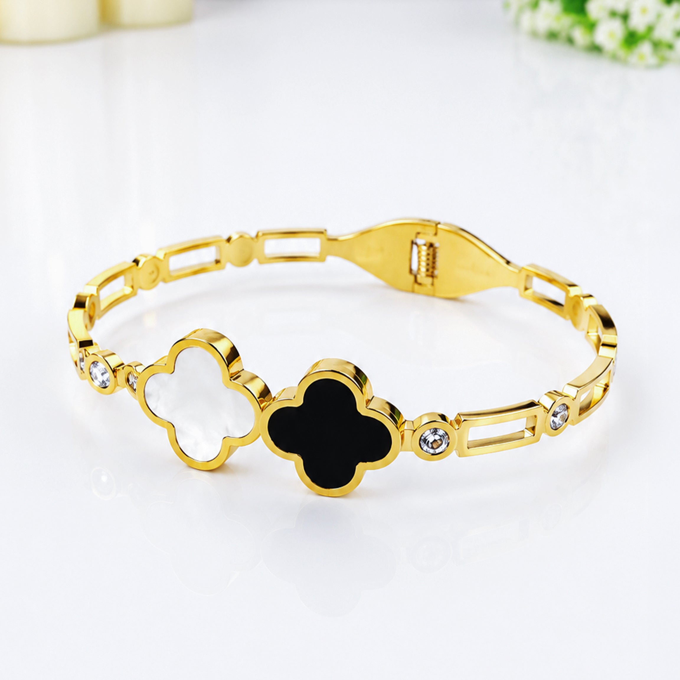 Gold bracelet with white and black quatrefoil charms and crystal accents