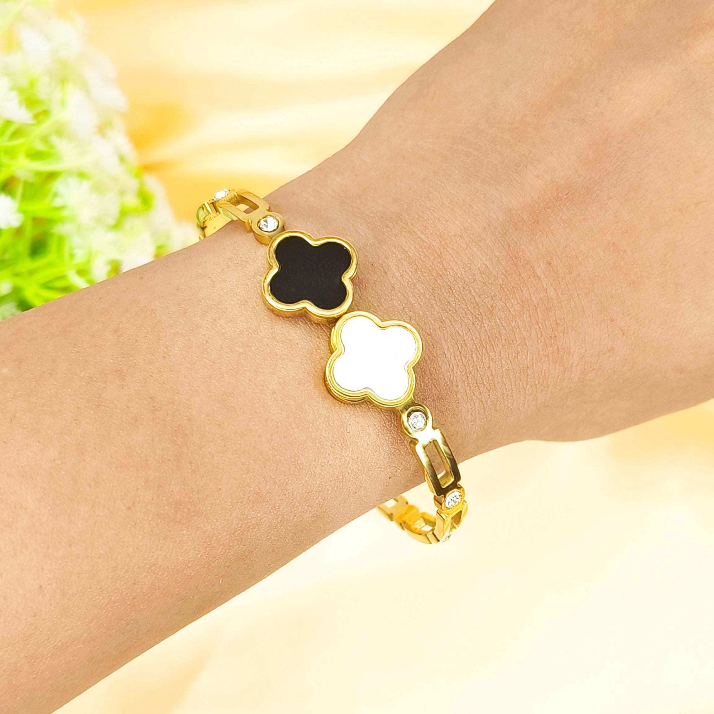 Gold clover bracelet with black and white enamel quatrefoil charms on a wrist