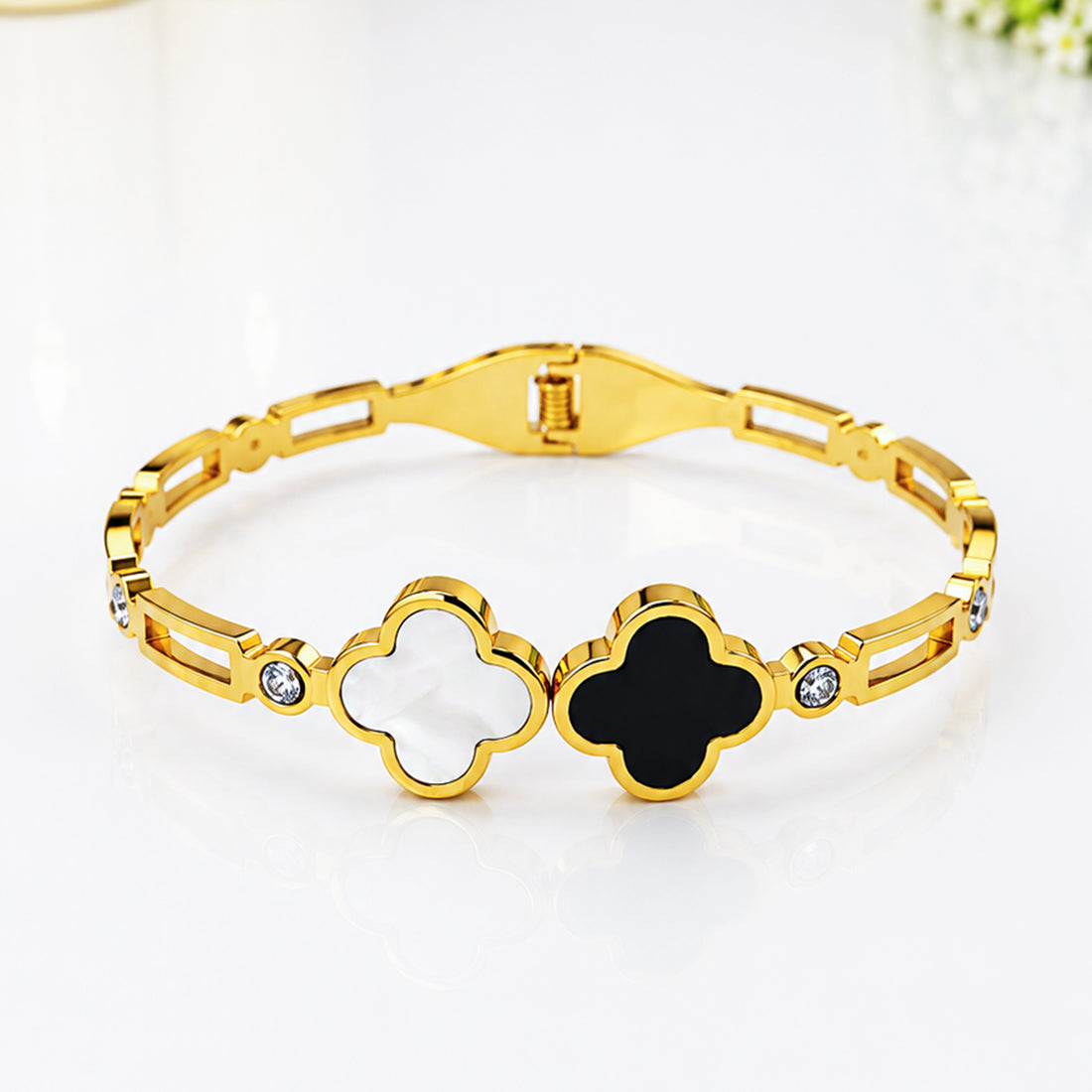 Gold-plated bracelet featuring black and white clover-shaped enamel charms and crystals.