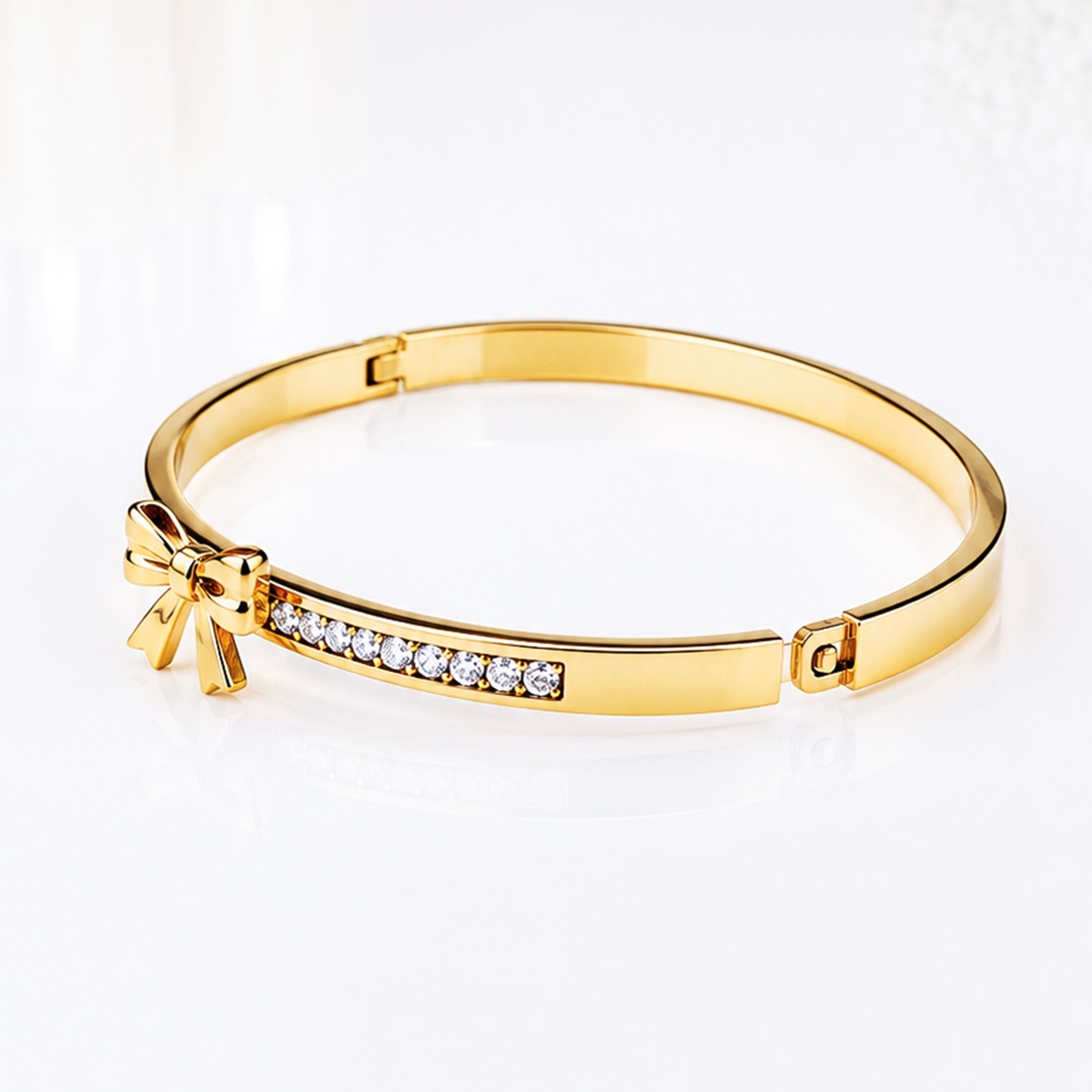 Elegant gold bangle bracelet with sparkling cubic zirconia stones and a bow detail.