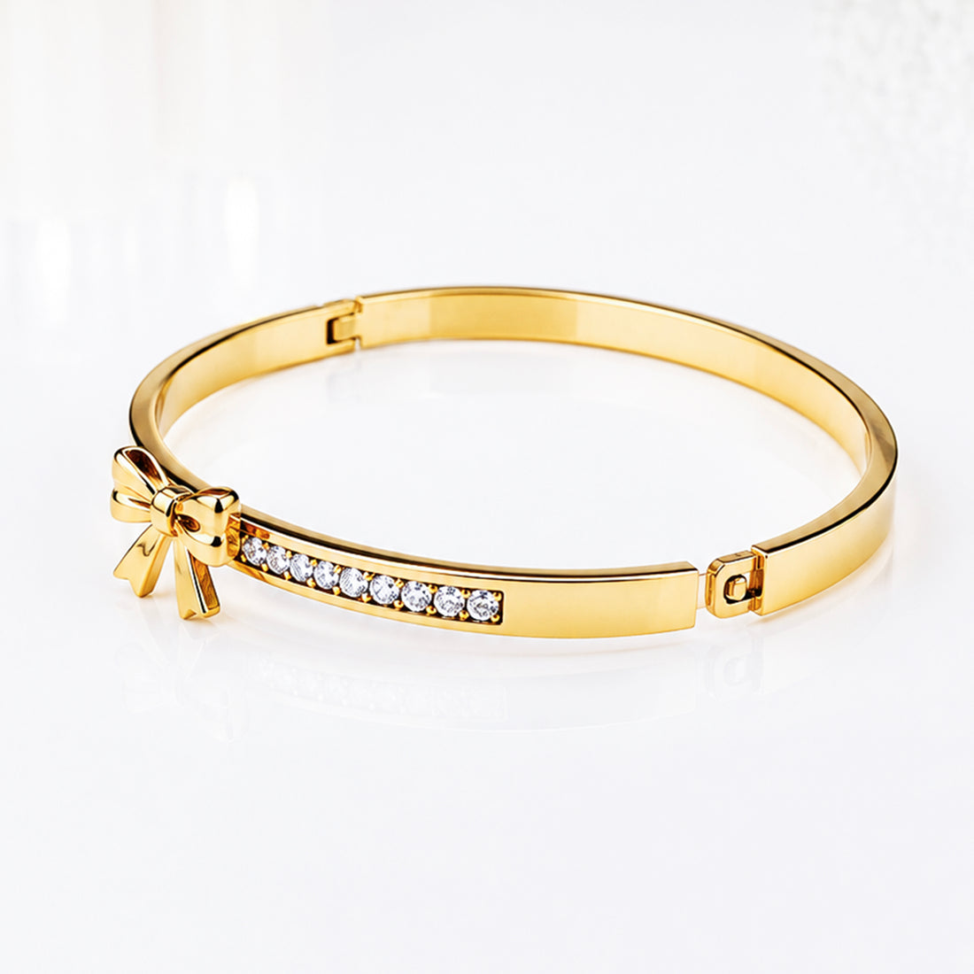 Elegant gold bangle bracelet with sparkling cubic zirconia stones and a bow detail.
