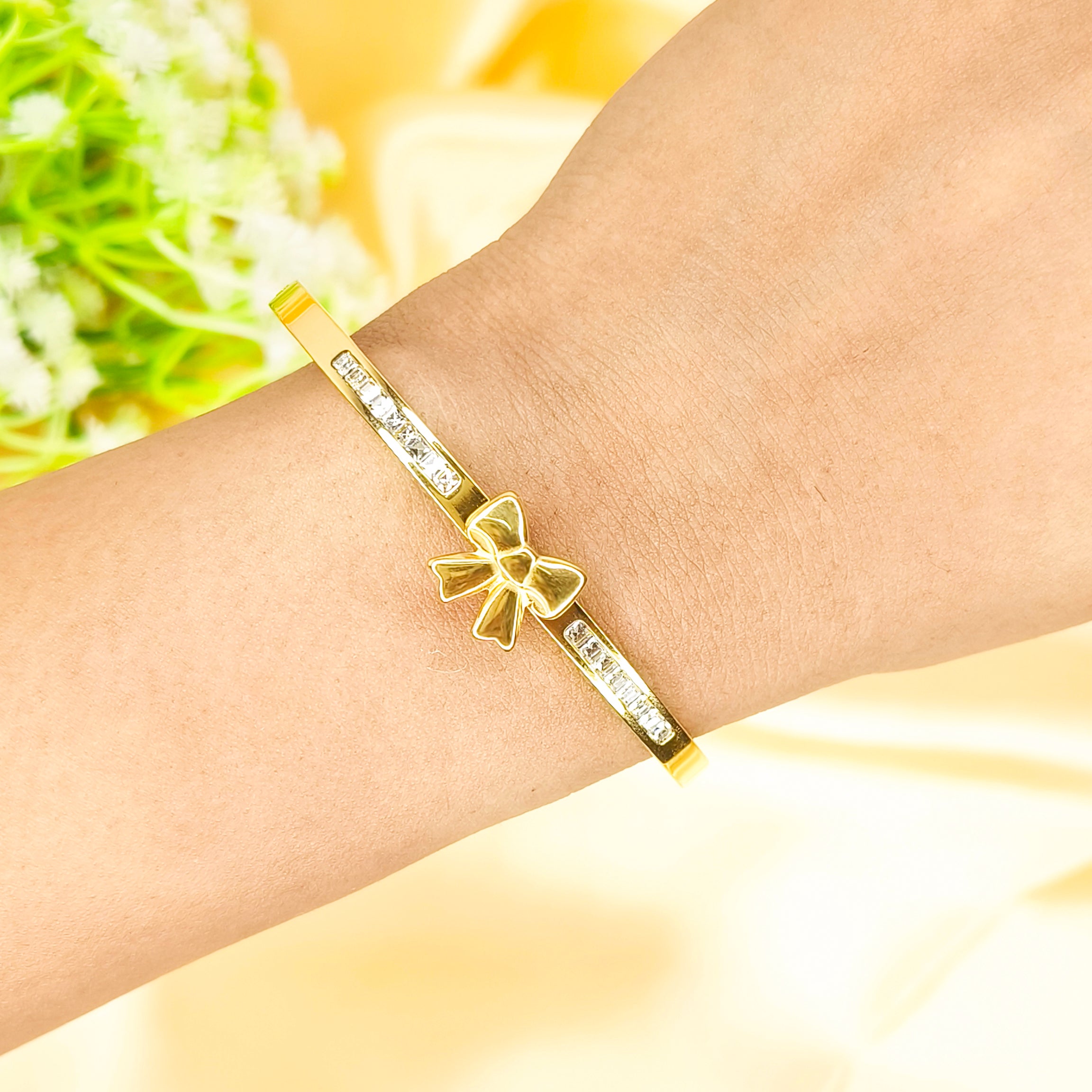 Gold bow charm bracelet with sparkling cubic zirconia accents on a wrist