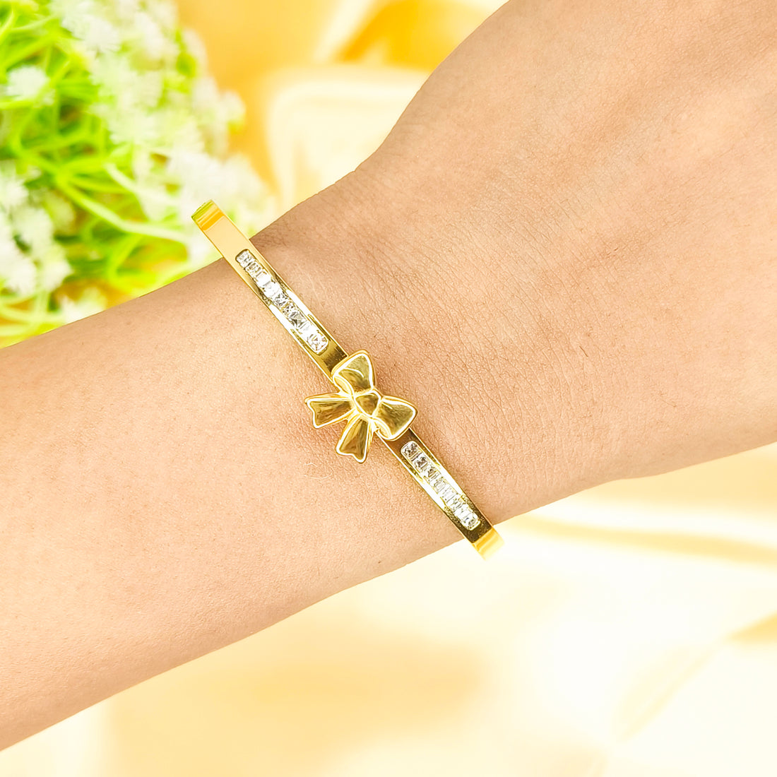 Gold bow charm bracelet with sparkling cubic zirconia accents on a wrist