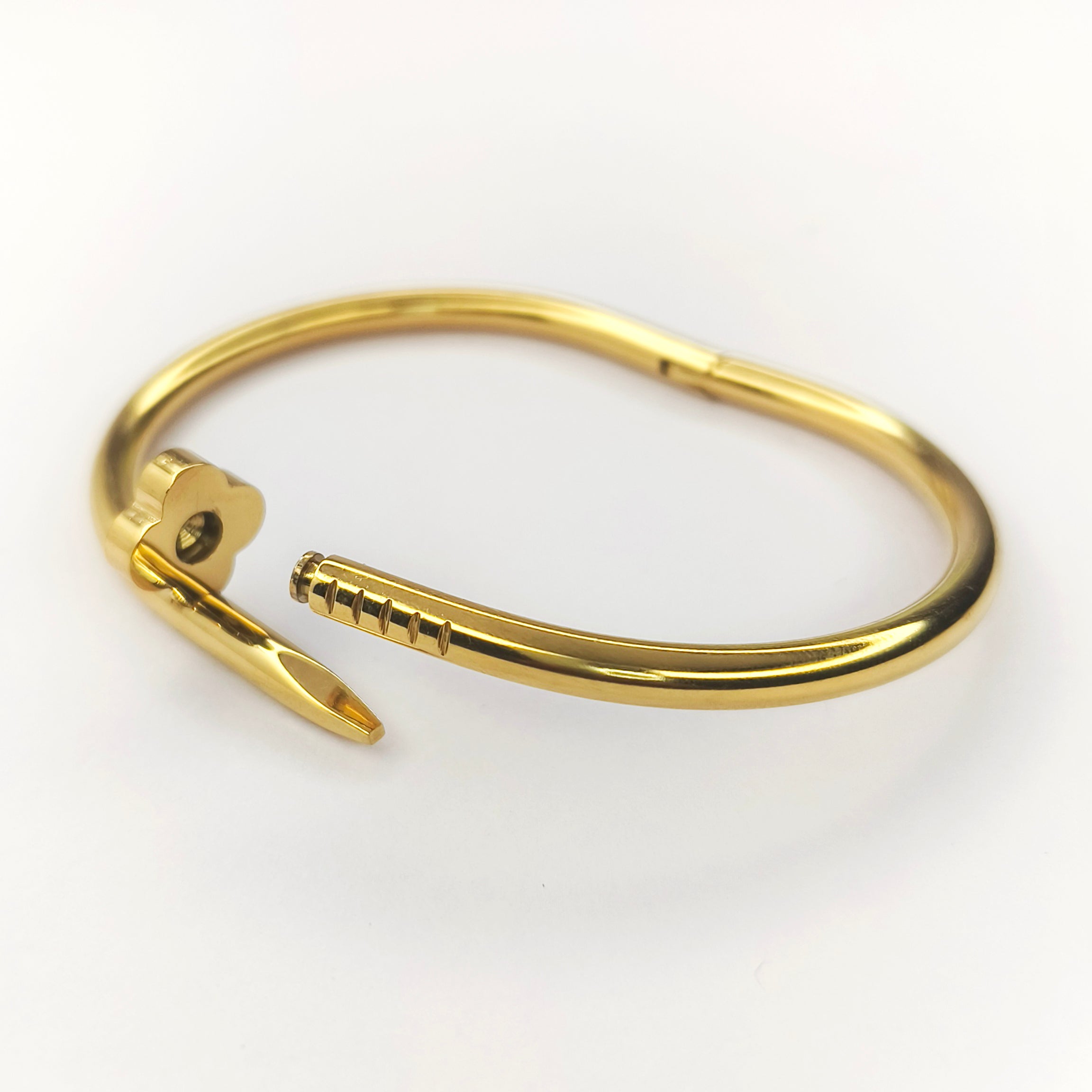 Elegant gold-plated bangle bracelet with a unique nail-shaped clasp design.