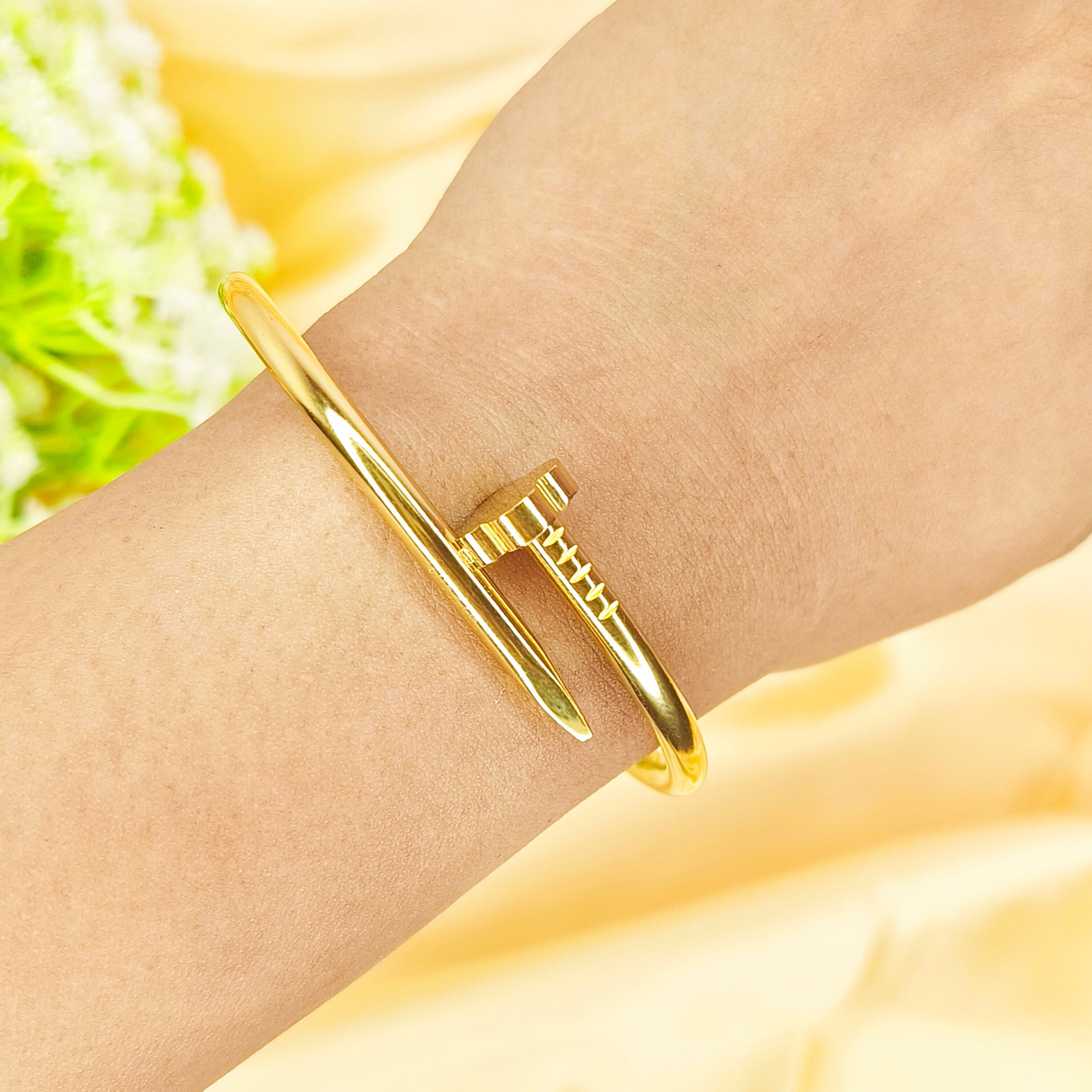 Elegant gold-plated nail-shaped bangle bracelet worn on a wrist.