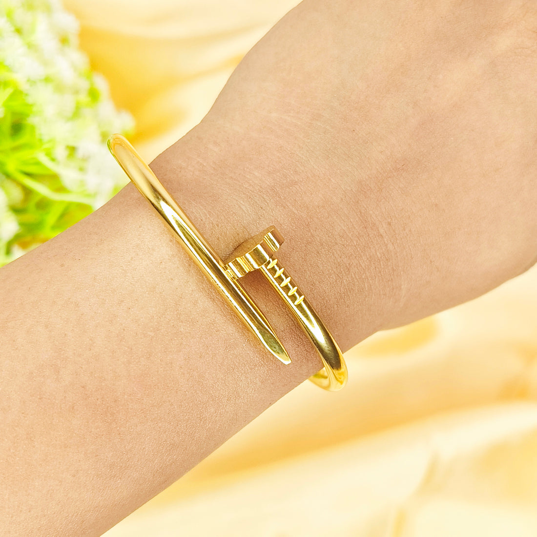Elegant gold-plated nail-shaped bangle bracelet worn on a wrist.