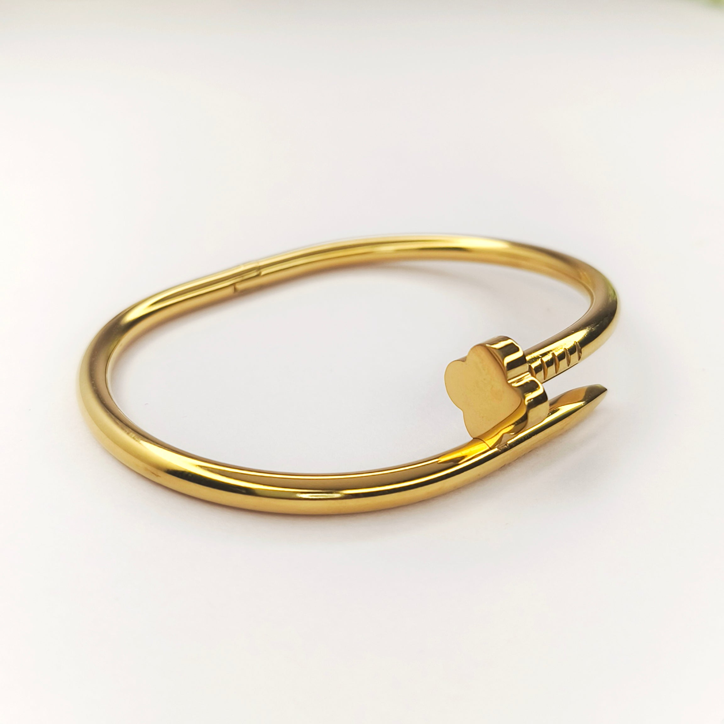 Gold-toned bangle bracelet featuring a heart-shaped arrow clasp design.
