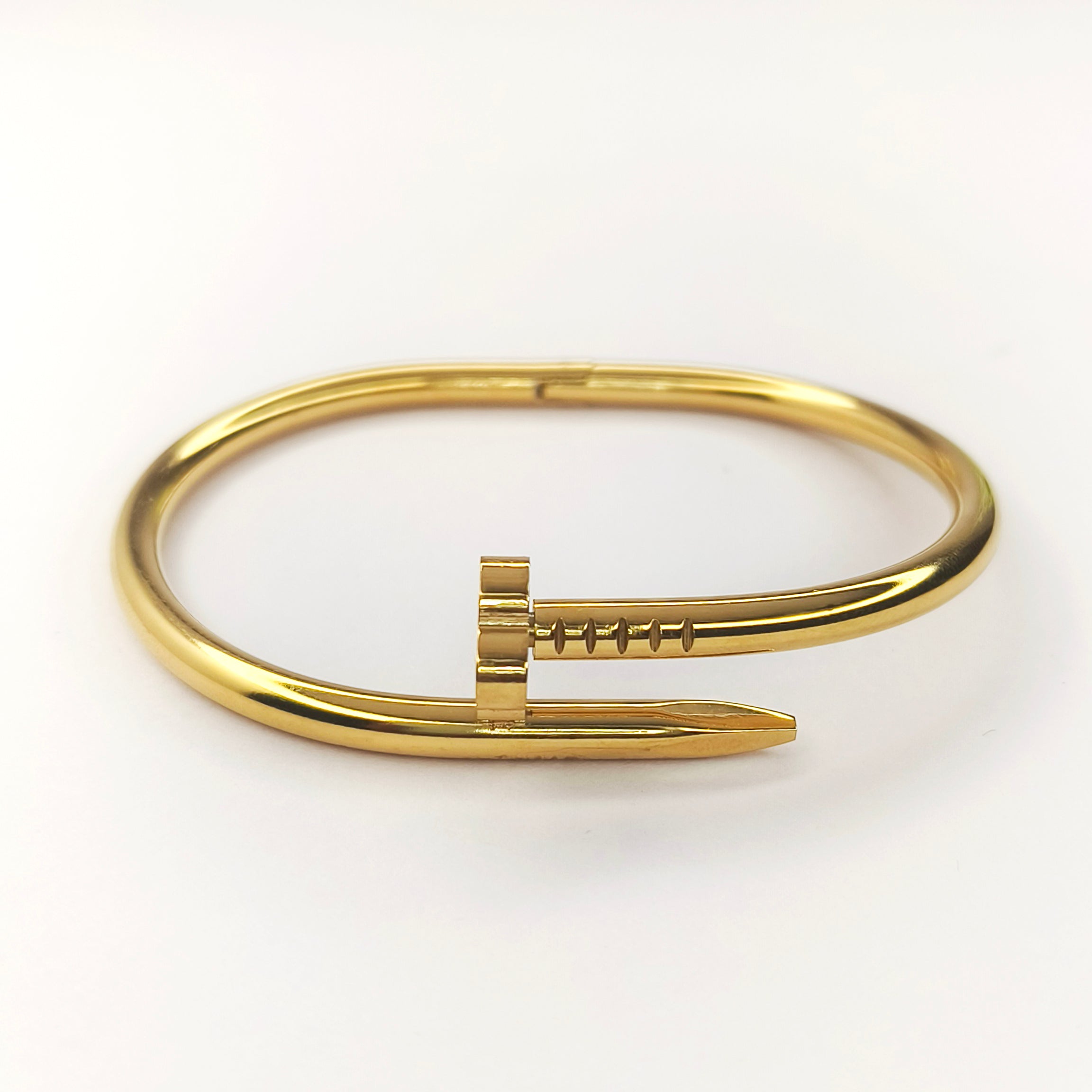 Elegant gold-tone bangle bracelet featuring a unique nail-shaped design element.