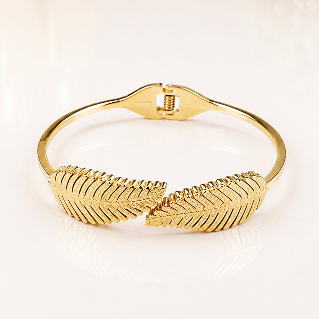 Elegant gold leaf design bangle bracelet with textured feather pattern.