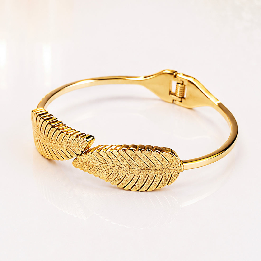 Elegant gold leaf design bangle bracelet with textured botanical details.