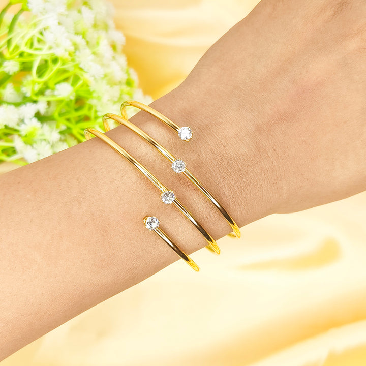 Set of four gold-plated open bangles with sparkling cubic zirconia crystals on a wrist