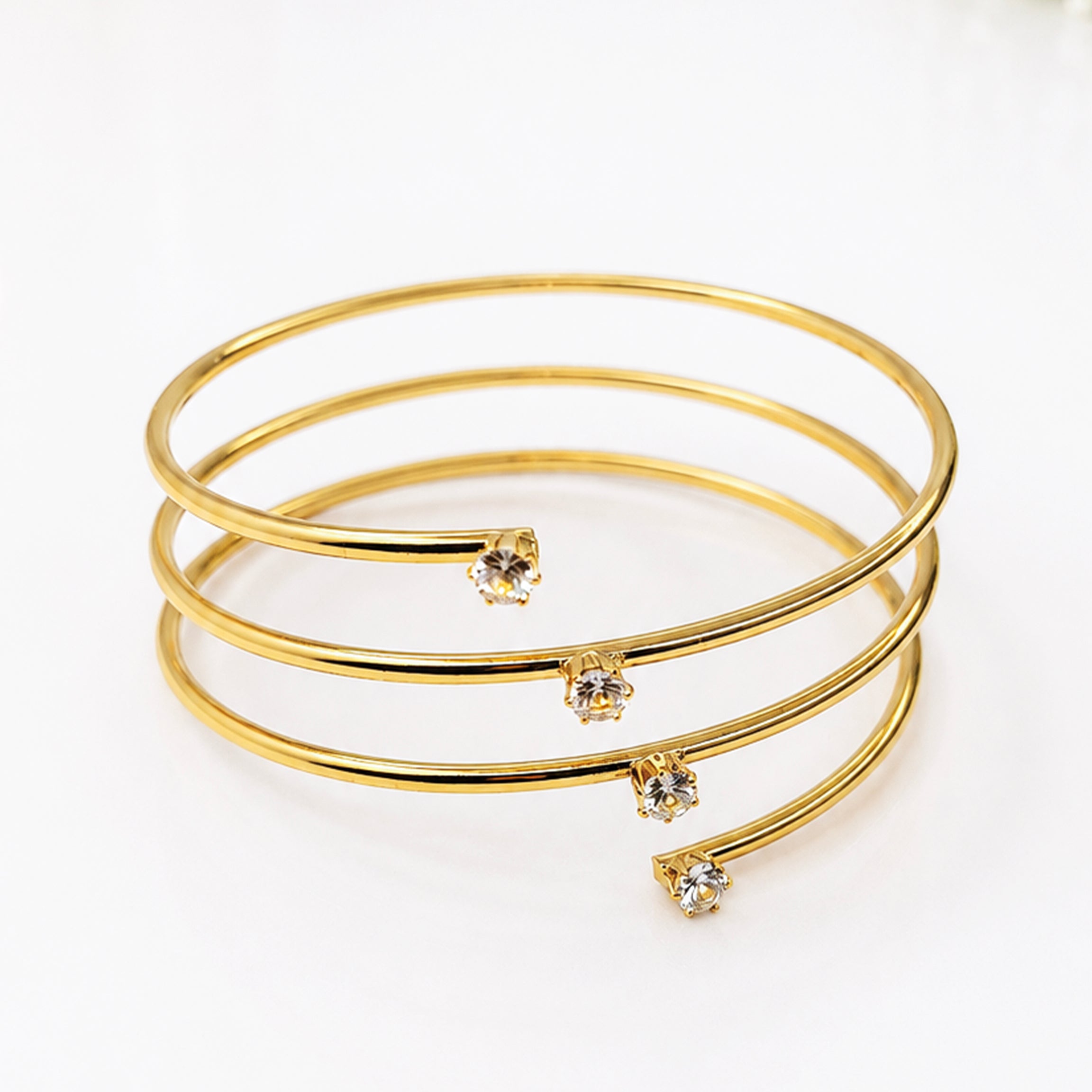 Elegant gold-tone spiral cuff bracelet with four sparkling crystal accents.