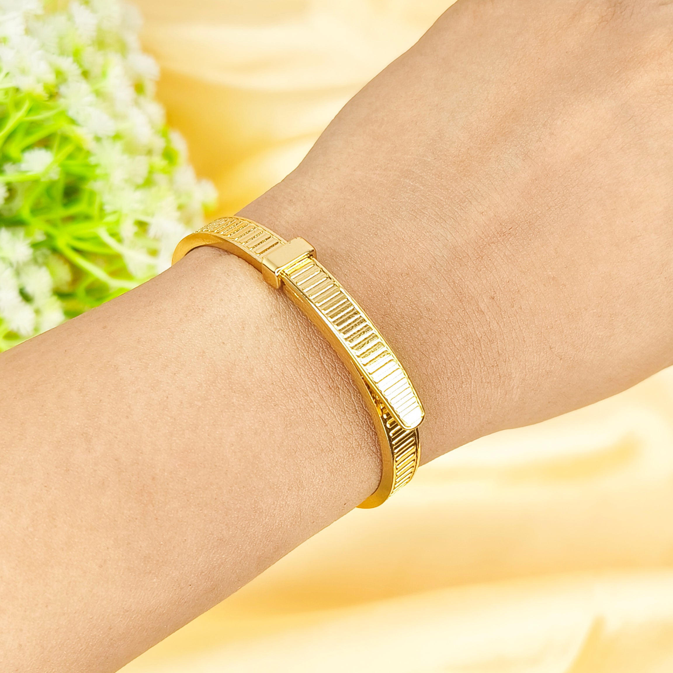 Gold-plated textured bangle bracelet worn on a woman's wrist.