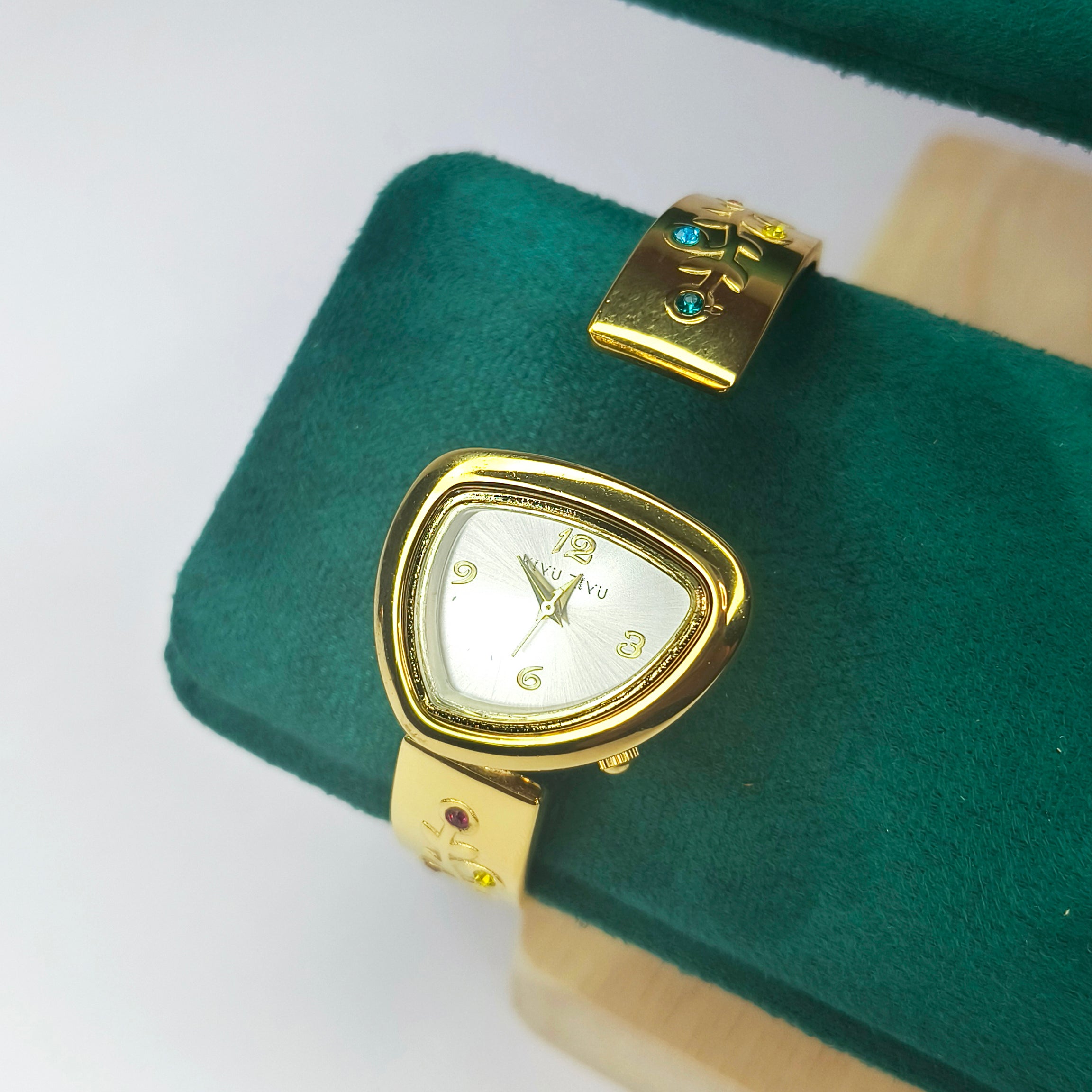 Gold-toned women's wrist watch with a triangular face on a green velvet display cushion