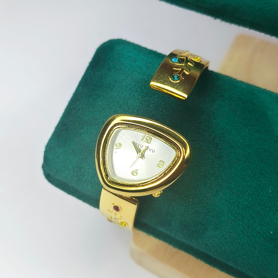 Gold-toned women's wrist watch with a triangular face on a green velvet display cushion