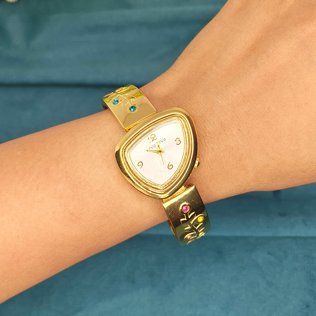 Elegant gold-tone women's watch with a triangular face and gemstone-embellished bracelet.