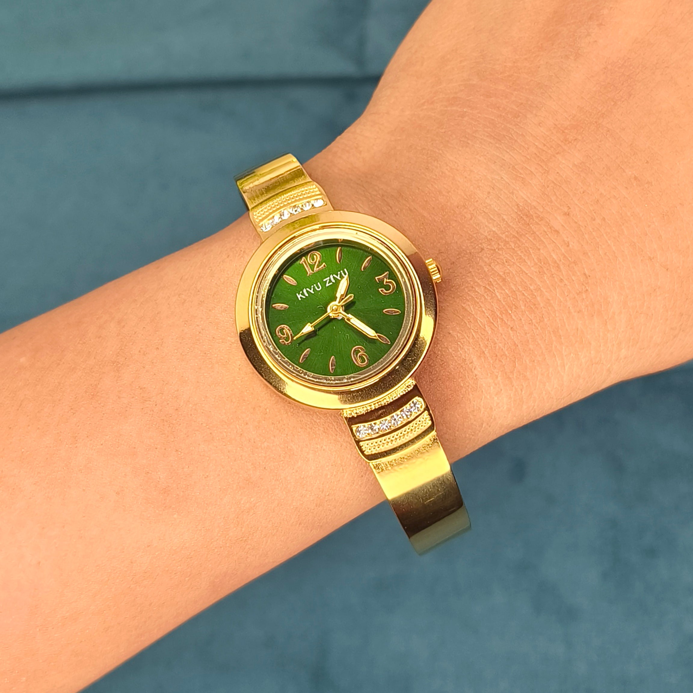 Gold luxury wristwatch with a green dial worn on a woman's wrist.